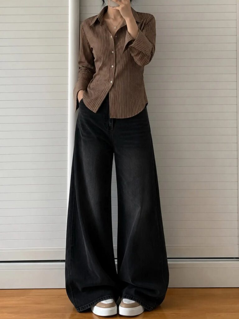 Person wearing a brown pinstriped shirt and very wide-leg black denim jeans.